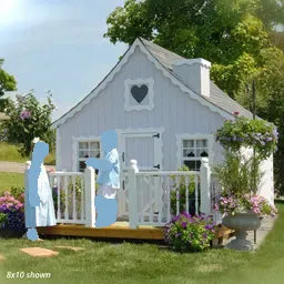 A small white cottage-style playhouse with deck and rail and heart shaped window