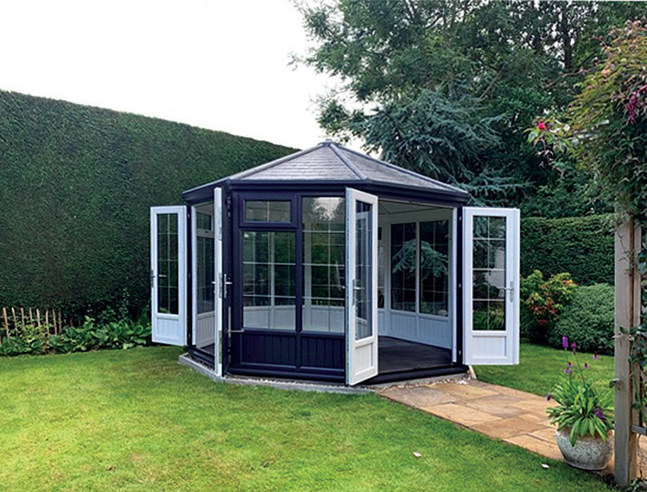Hexagonal garden building with open doors in a garden setting.