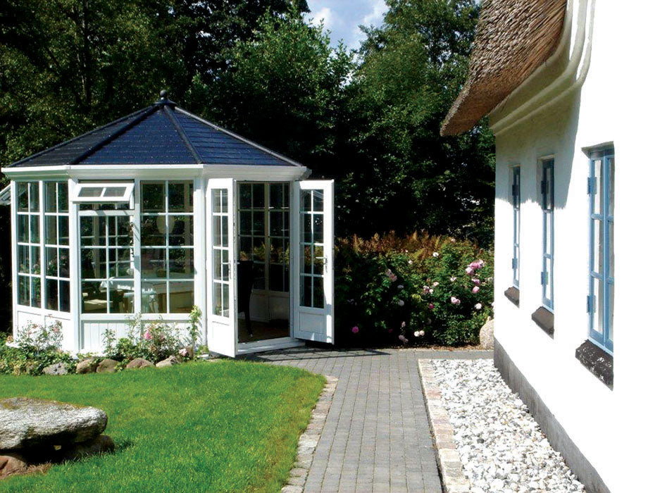 White garden room with tile black roof, double doors in a garden setting